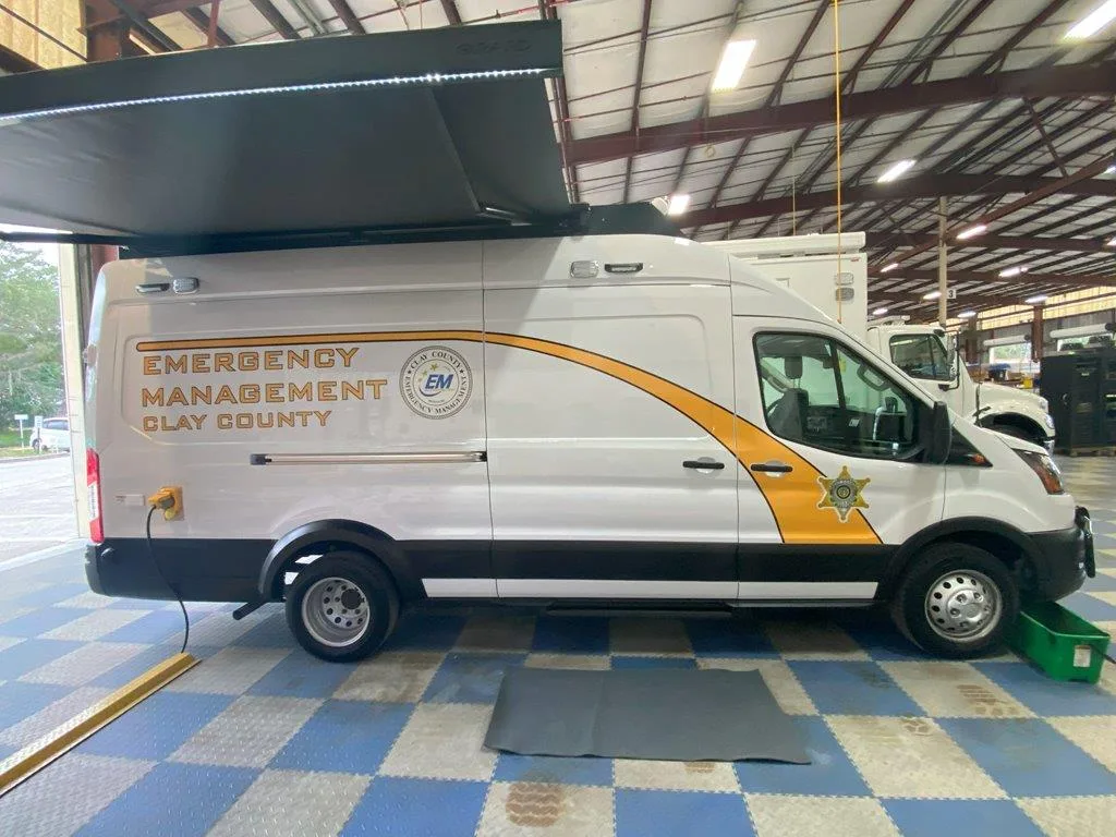 Frontline Communications CRU-22 Mobile Command vehicle with the awning extended parked inside a garage.