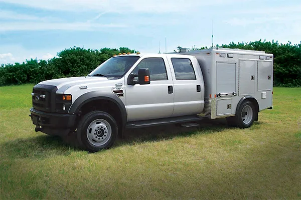 Frontline Communications EOD Bomb unit parked outside on the grass on a cloudy day.