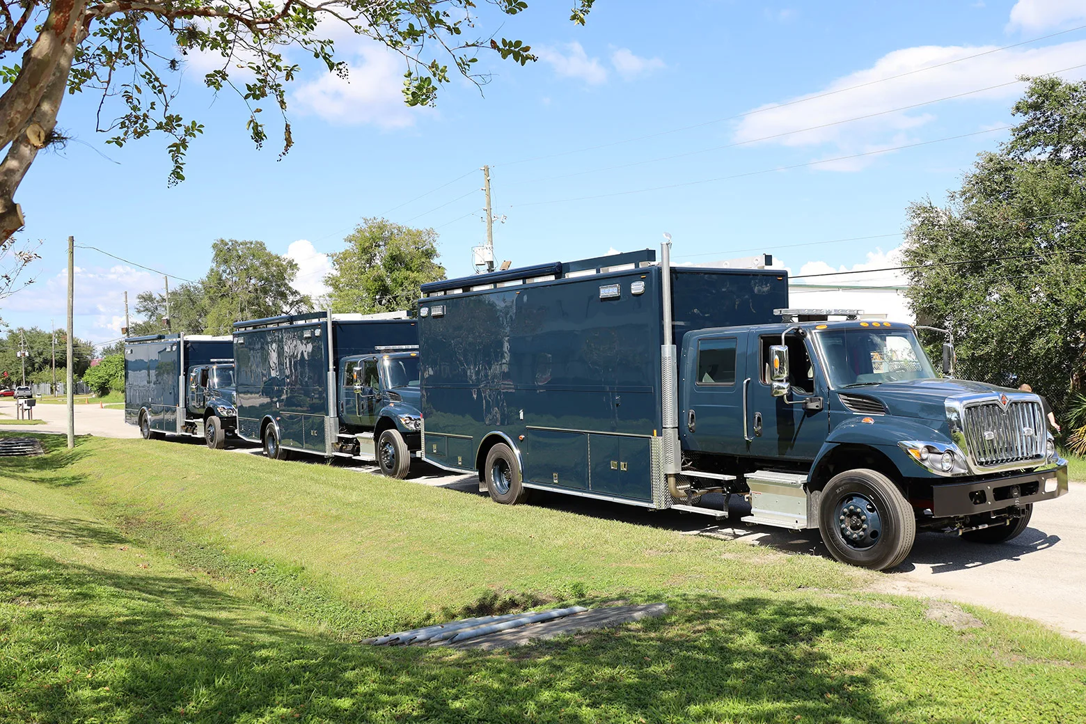 Three US Navy C-36 EOD Bomb units parked outside near the Frontline Communications building on a sunny day.