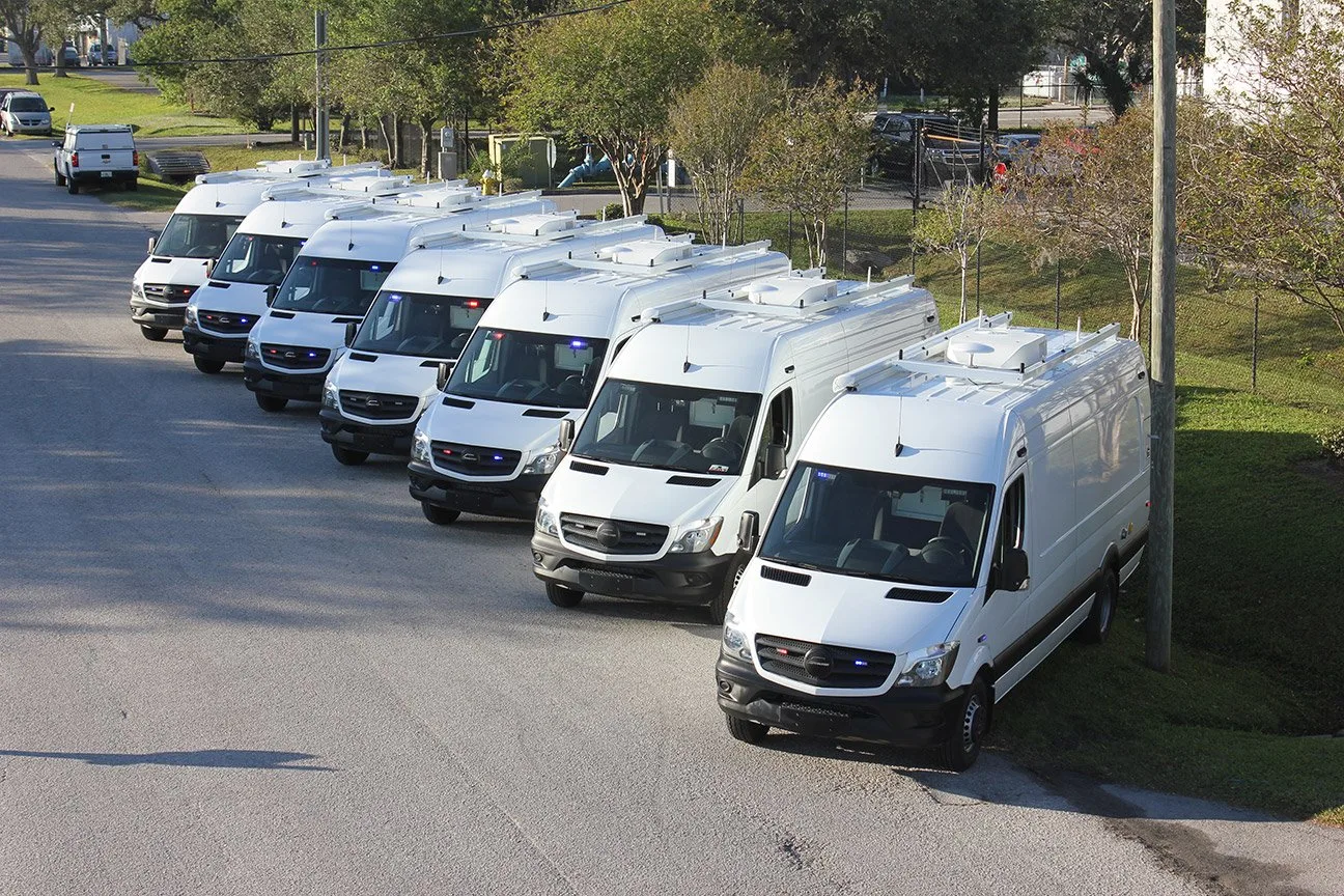 Seven FBI C-24 Mobile Command vehicles parked outside near the Frontline Communications building.