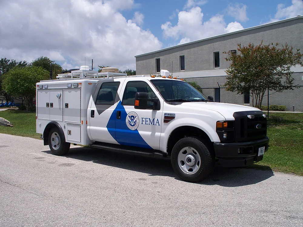 FEMA C-25 RRV parked outside near the Frontline Communications building on a sunny day.