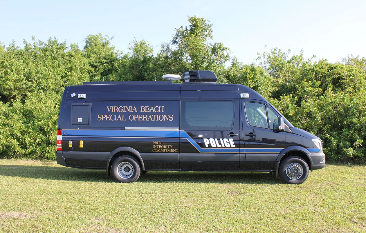 Frontline Communications Hostage Negotiation vehicle parked outside near trees on a sunny day.