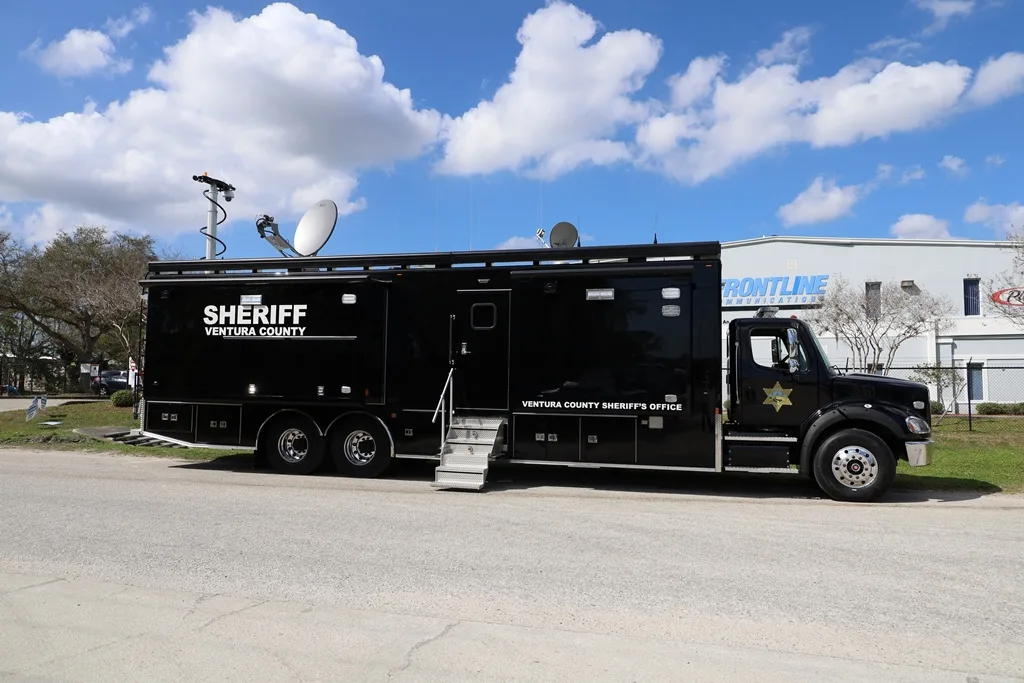 Frontline Communications C-45X-4 Mobile Command vehicle parked outside near the building on a cloudy day.