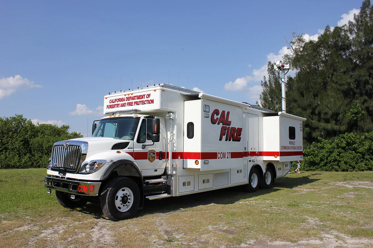 Frontline Communications C-40X-3 Mobile Communications vehicle parked outside near trees on a sunny day.