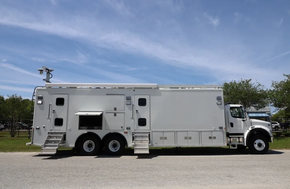 Frontline Communications C-40X-2 Mobile Command vehicle parked outside near trees on a cloudy day.
