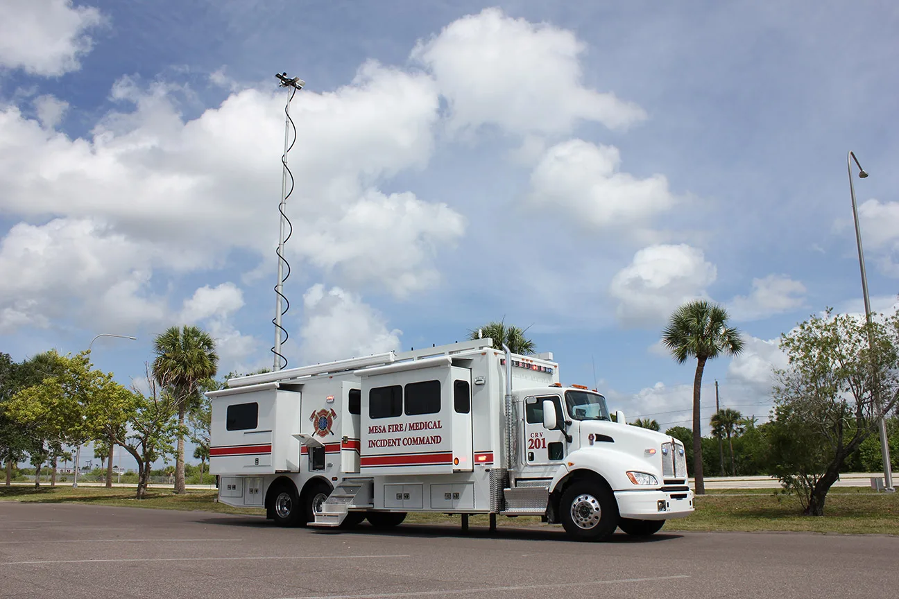 Frontline Communications C-40X-3 Incident Command vehicle parked outside in a parking lot near trees on a cloudy day.