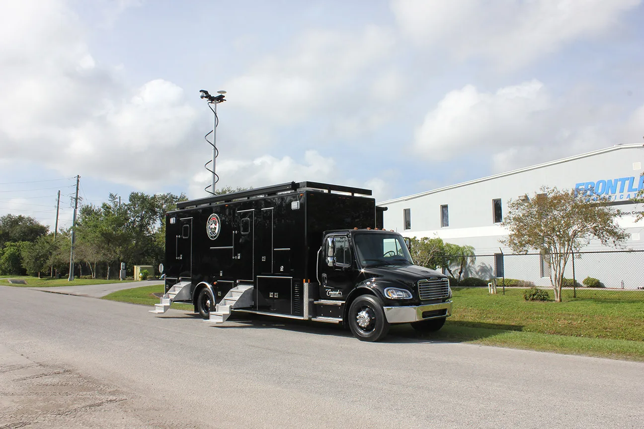 Mid-Size Mobile Command vehicle parked outside near the Frontline Communications building on a cloudy day.