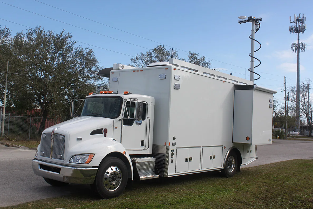Driver's side of a Frontline Communications C-32X Mobile Command vehicle parked outside on a cloudy day.