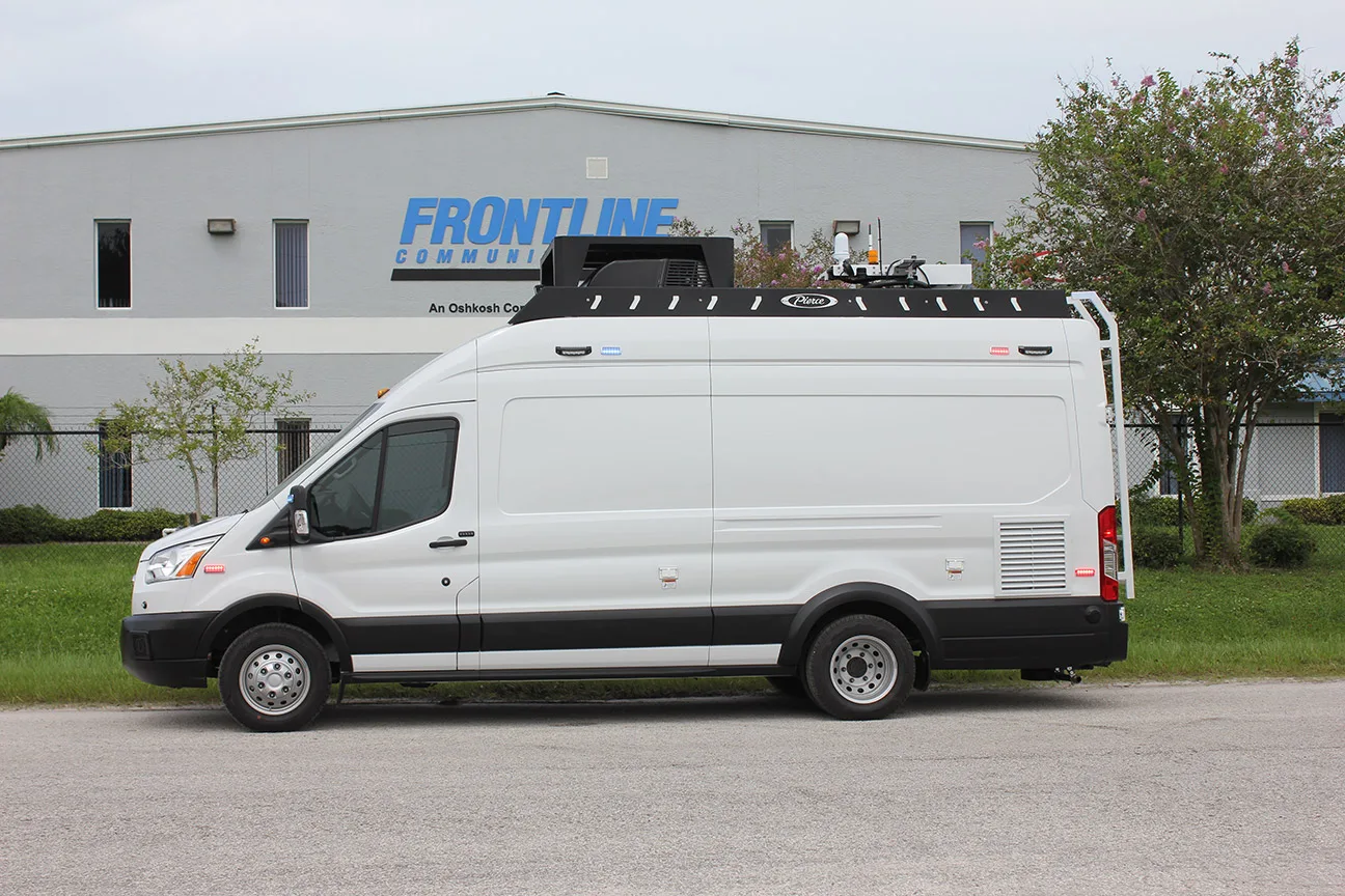 C-24 Small Mobile Command vehicle parked outside near the Frontline Communications building on a cloudy day.