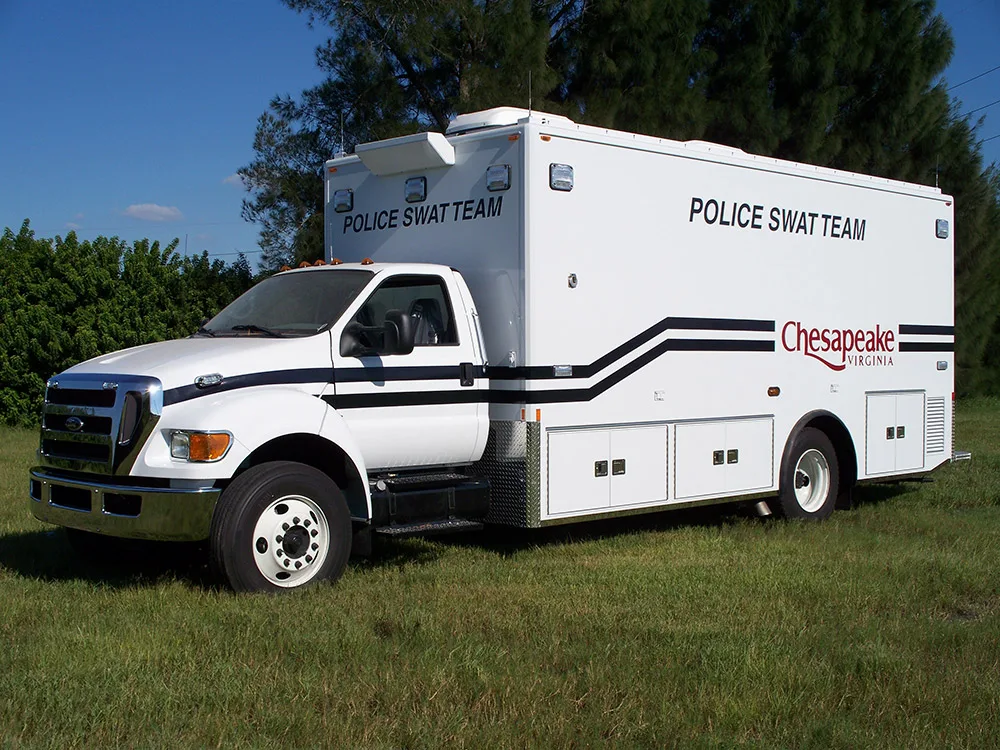 Frontline Communications C-33 SWAT vehicle parked outside in grass on a sunny day.