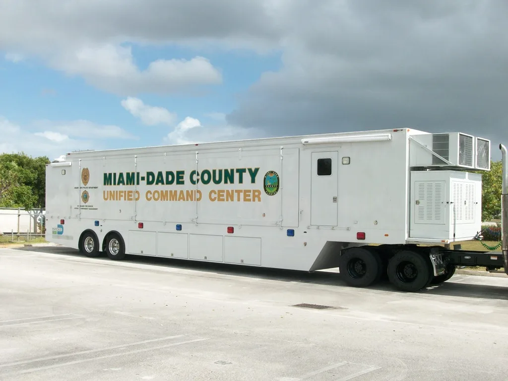 Miami Dade Police Frontline Communications C-53TX Trailer Refurbishment vehicle parked outside in a parking lot on a cloudy day.
