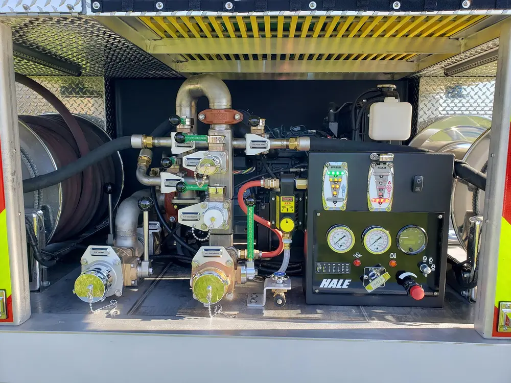 Exterior view of small fire truck showing cab, body compartments, and wheel/tire area.