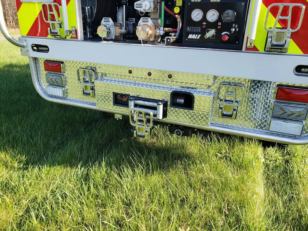Exterior view of small fire truck showing cab, body compartments, and wheel/tire area.