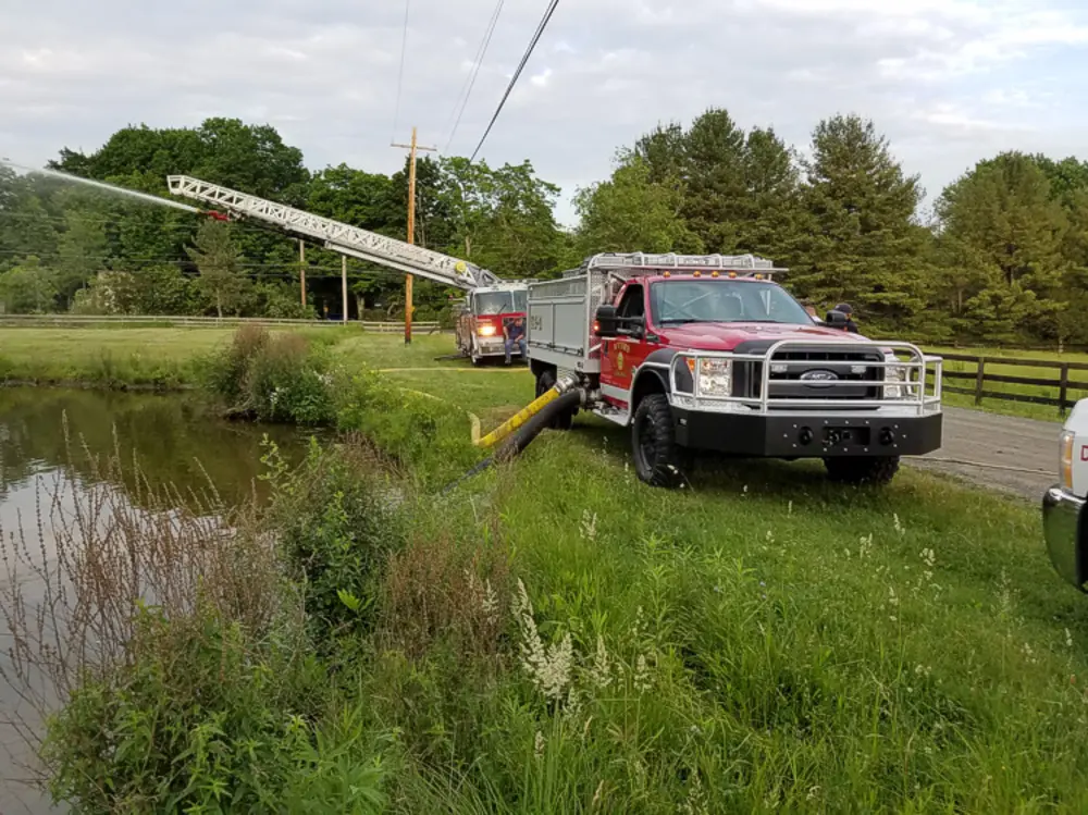 Exterior view of small fire truck showing cab, body compartments, and wheel/tire area.