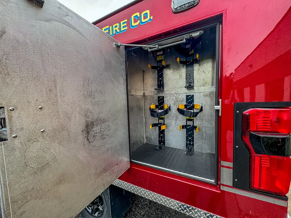 Open vertical compartment with mounted long-handled tools.