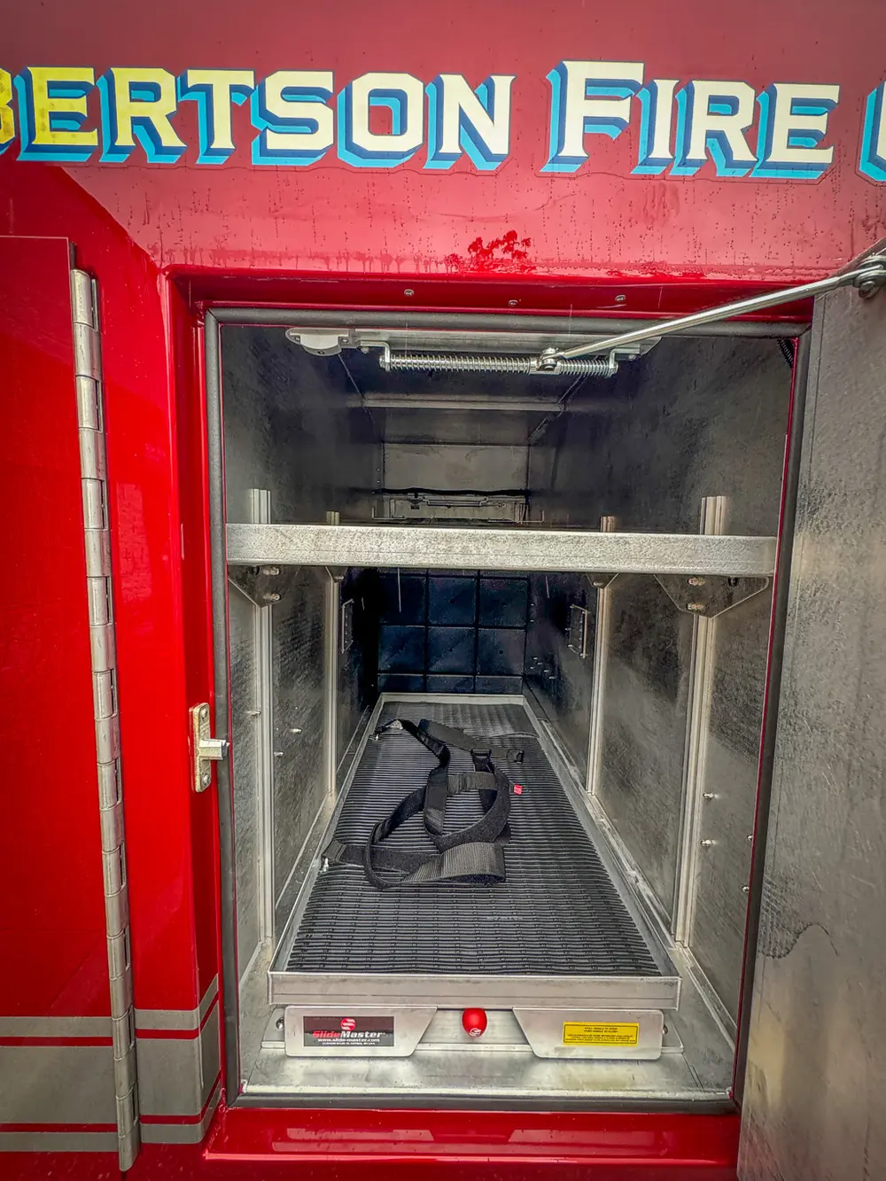 Compartment interior with shelves and black bag on floor.