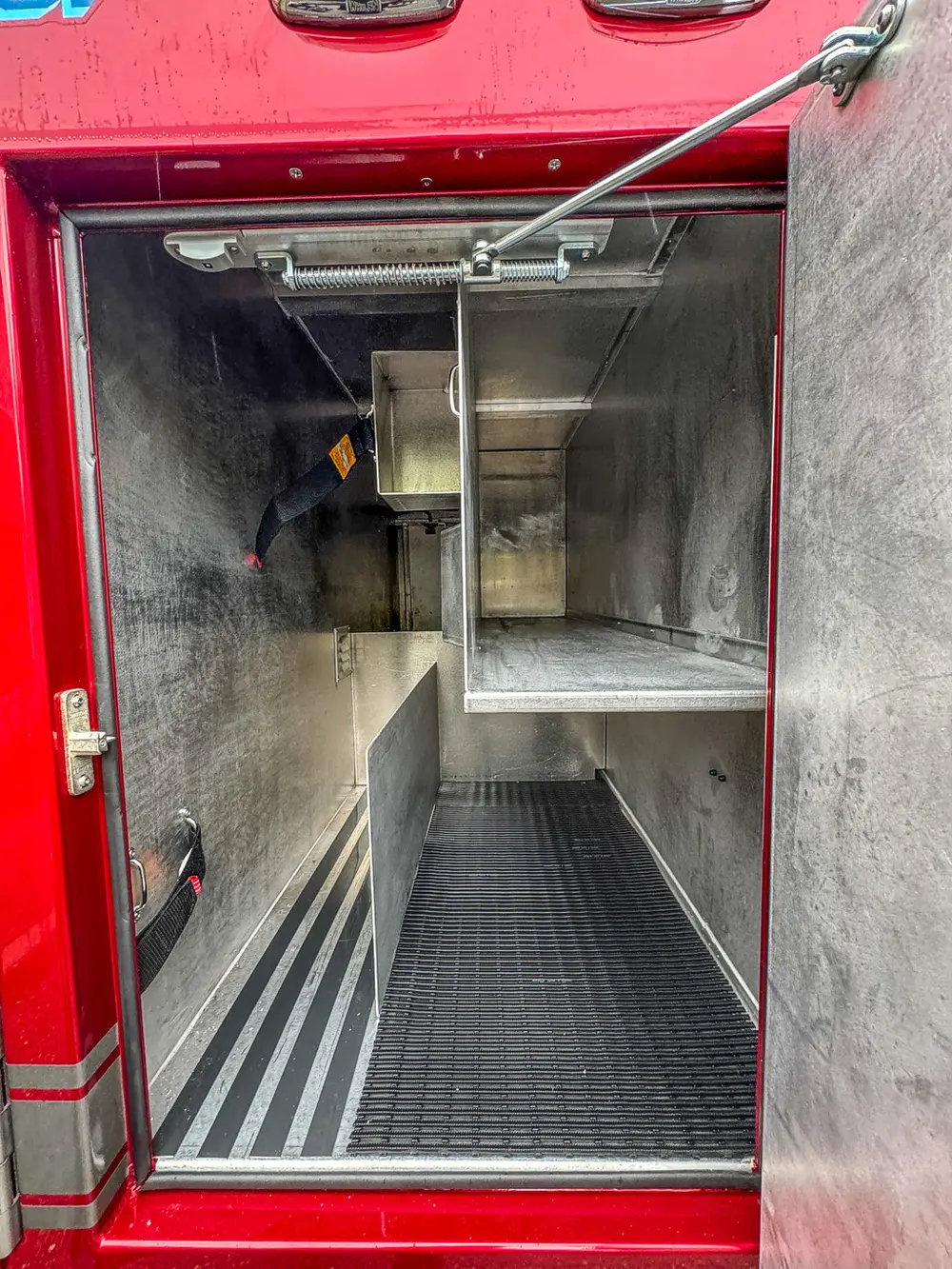 Long compartment interior with ribbed floor and side rails.