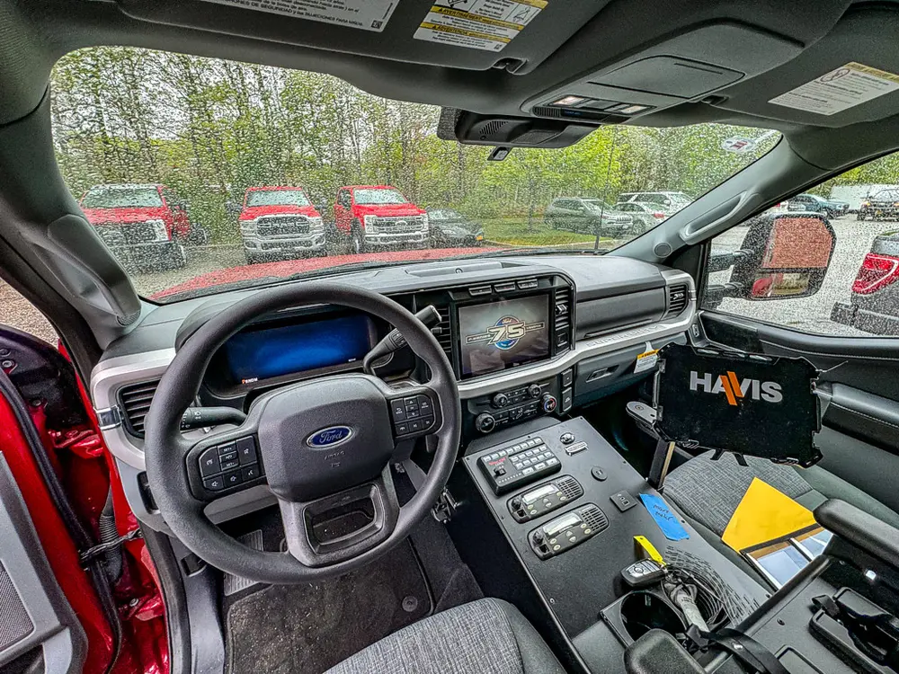 Driver cockpit view with steering wheel, dash, and console controls.