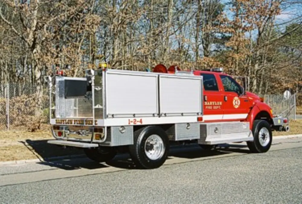 Exterior view of small fire truck showing cab, body compartments, and wheel/tire area.