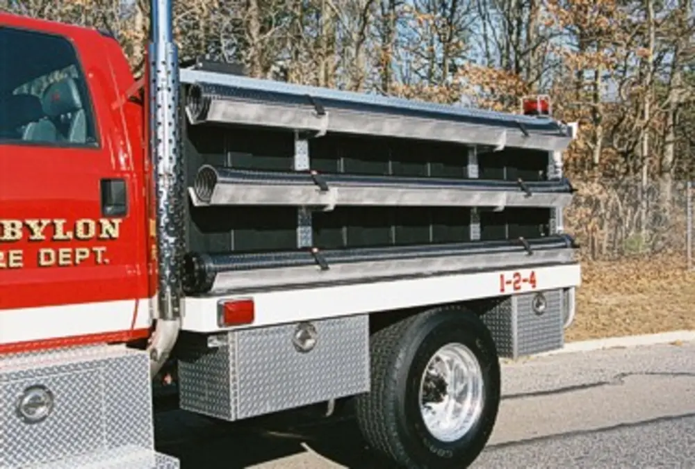 Exterior view of small fire truck showing cab, body compartments, and wheel/tire area.