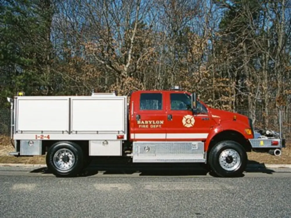 Exterior view of small fire truck showing cab, body compartments, and wheel/tire area.