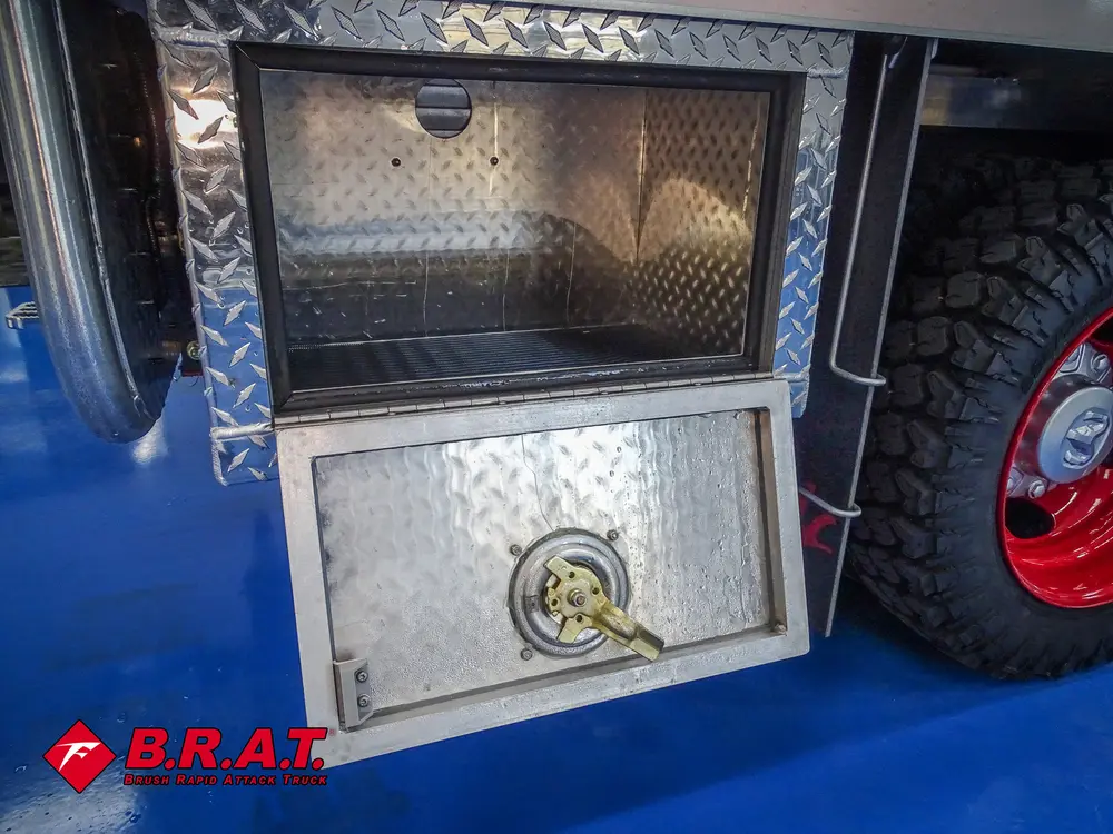 Open lower diamond-plate compartment beneath side body panel.