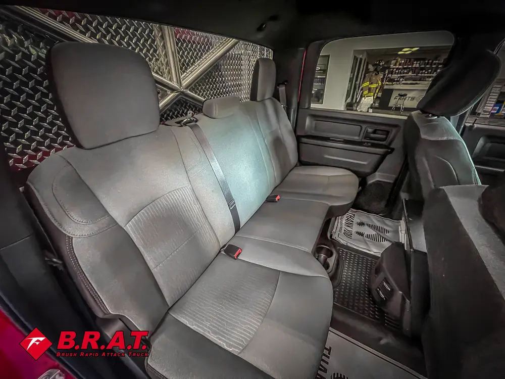 Rear bench seat area with gray upholstery and floor mat.