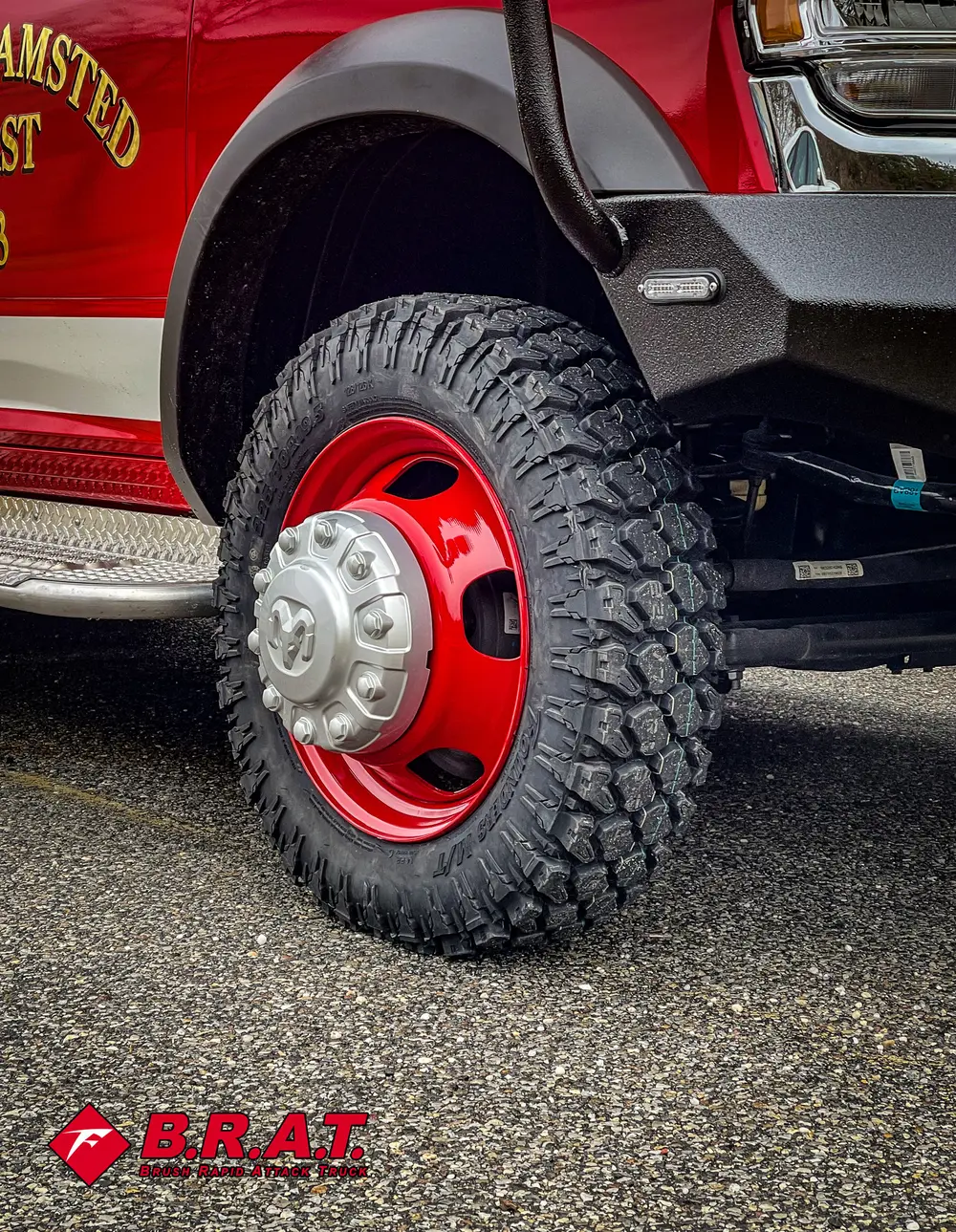 Close-up of off-road rear tire and red steel wheel.