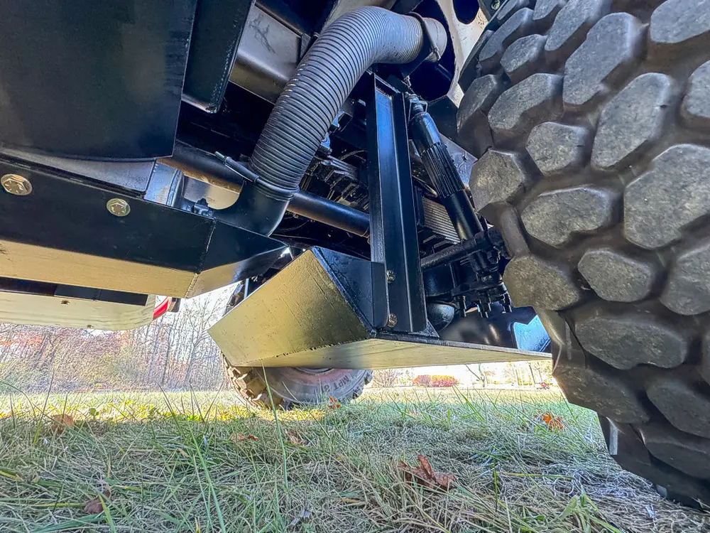 Undercarriage corner close-up with suspension arm and tire.