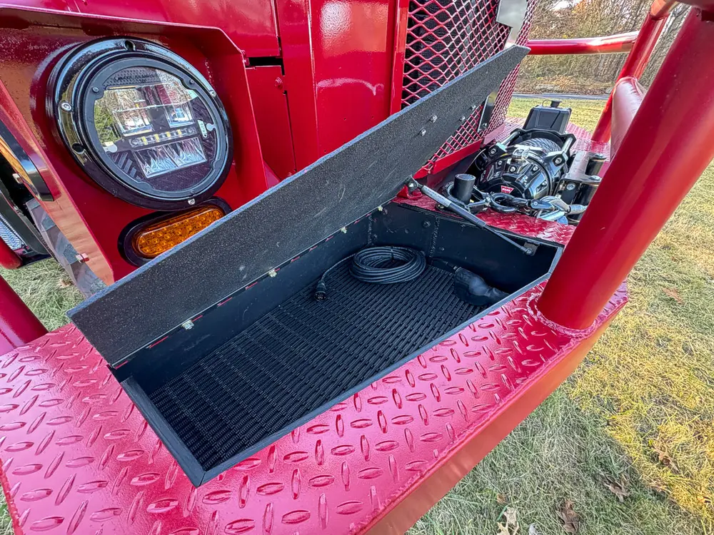 Open front step compartment showing black storage tray beneath headlight.
