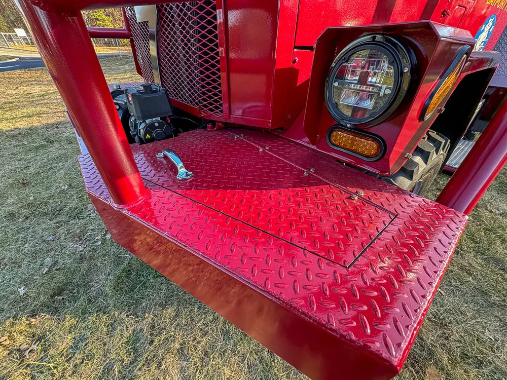 Front bumper step close-up with compartment door closed.