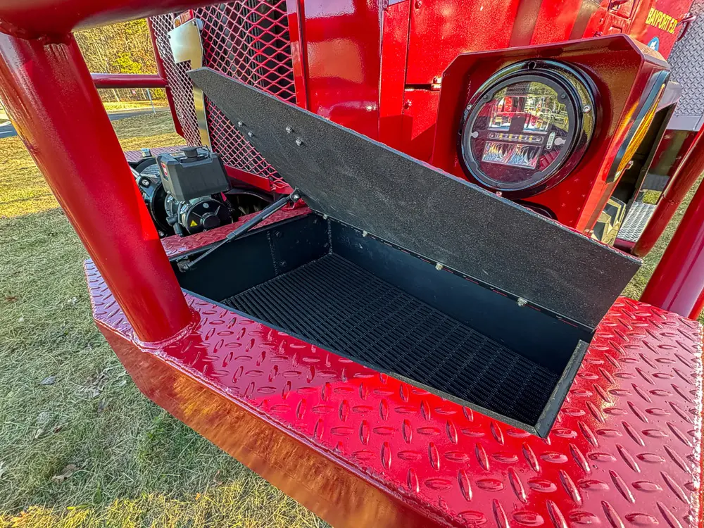 Open front step compartment from opposite side showing storage tray.