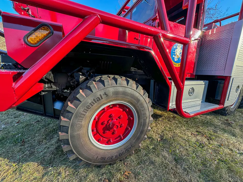 Mid-side close-up of front wheel and lower cab entry area.