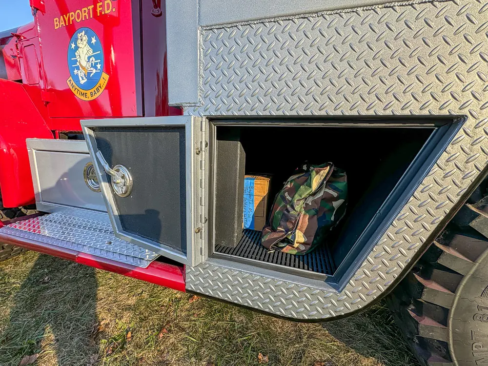 Open side compartment with fold-down door and stored gear bag.