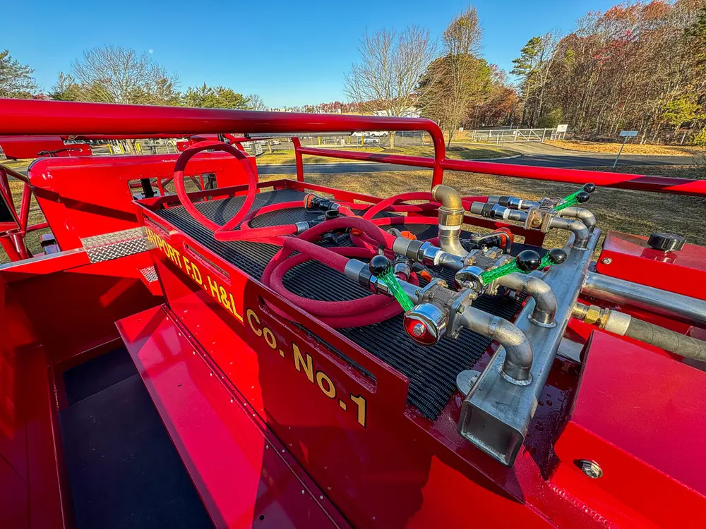 Top deck pump plumbing and controls with hose lines routed across rails.