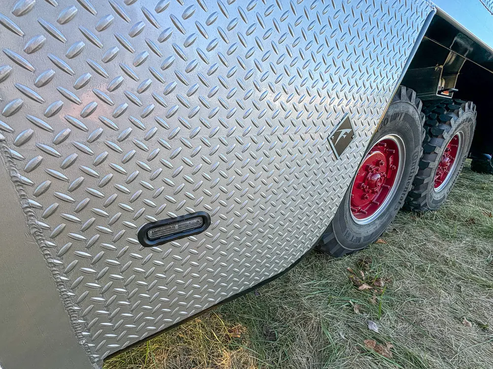 Diamond-plate side body close-up with flush latch on lower panel.
