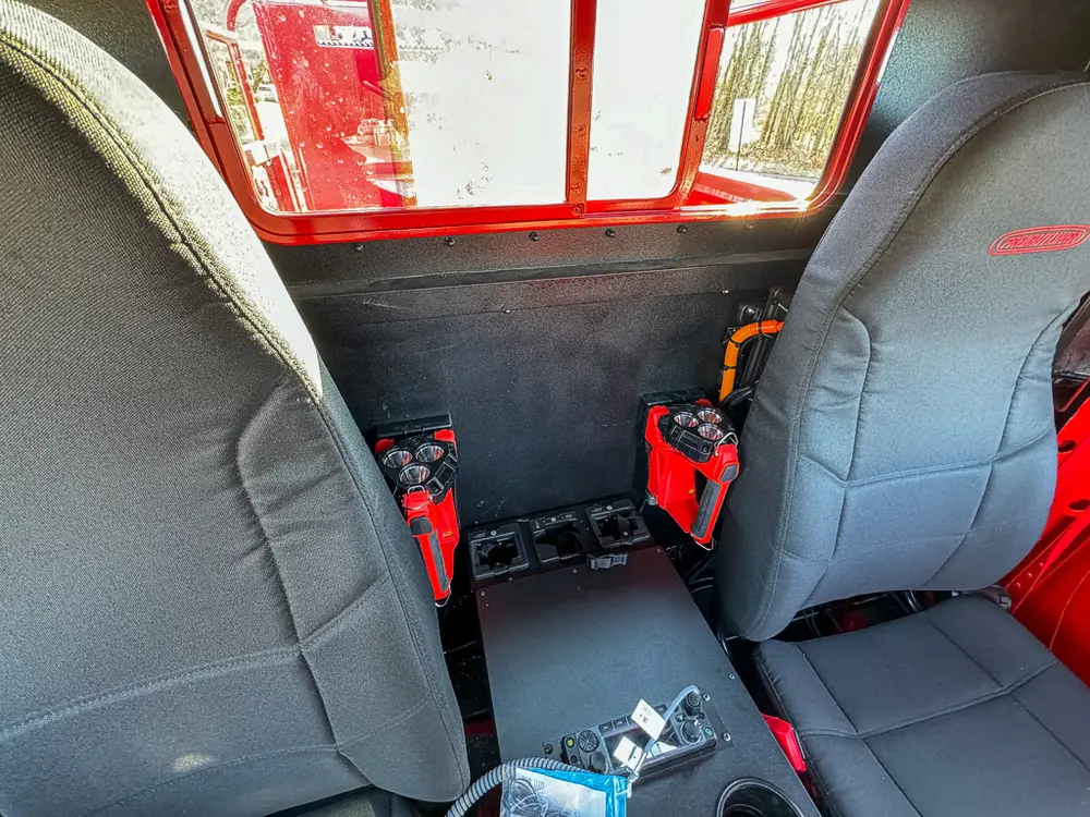 Rear interior area behind seats with extinguisher and equipment on floor.