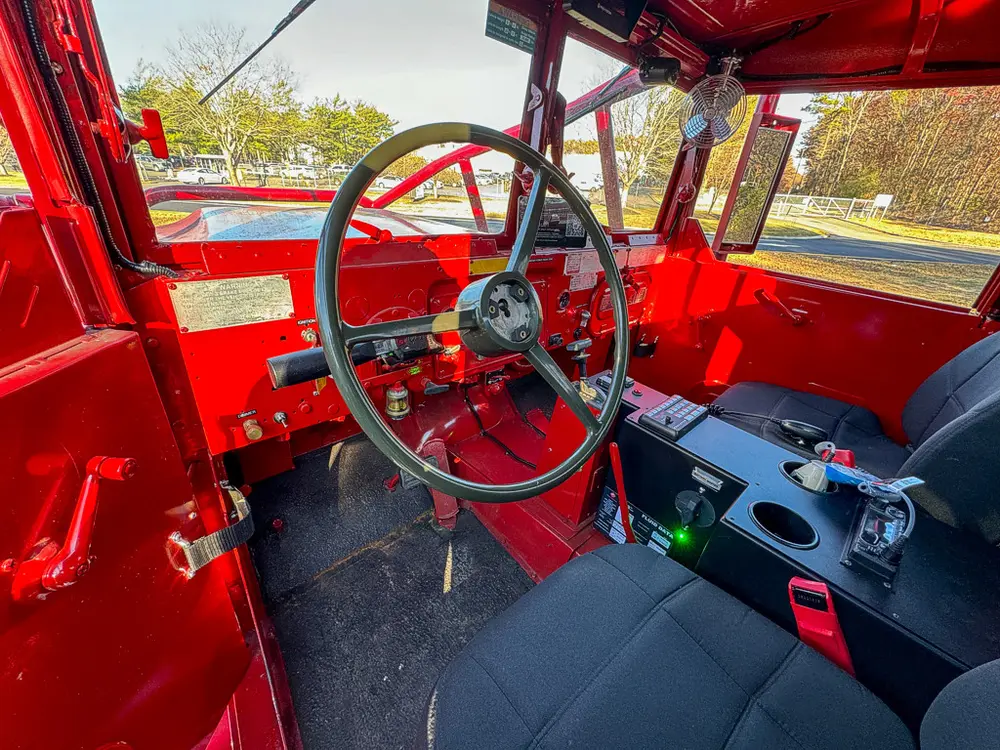 Front cabin view from open side door showing steering area.