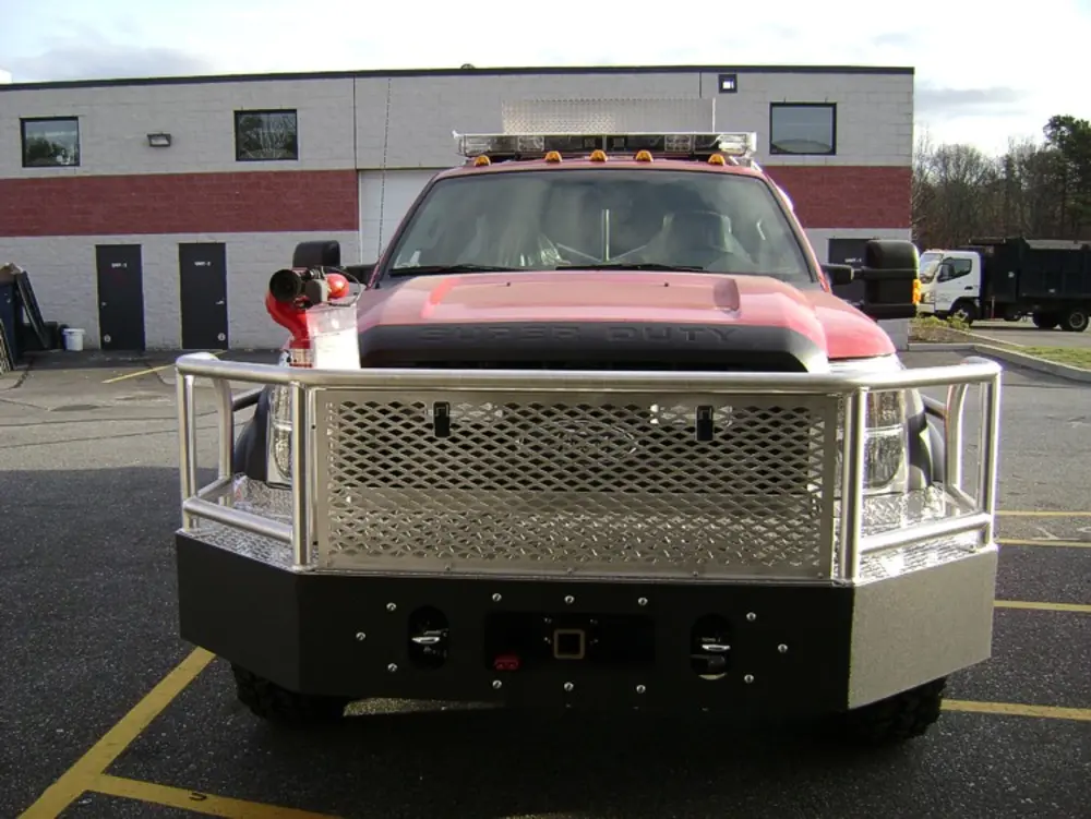 Exterior view of small fire truck showing cab, body compartments, and wheel/tire area.