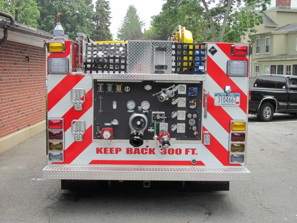 Exterior view of small fire truck showing cab, body compartments, and wheel/tire area.
