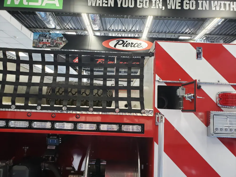 Exterior view of small fire truck showing cab, body compartments, and wheel/tire area.