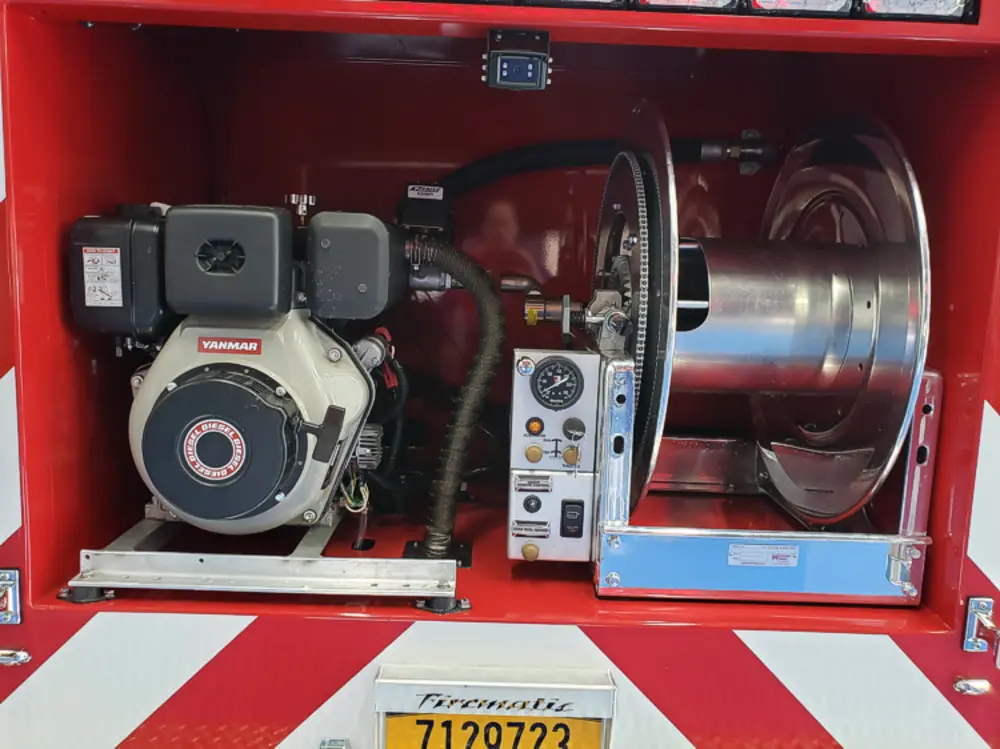 Exterior view of small fire truck showing cab, body compartments, and wheel/tire area.