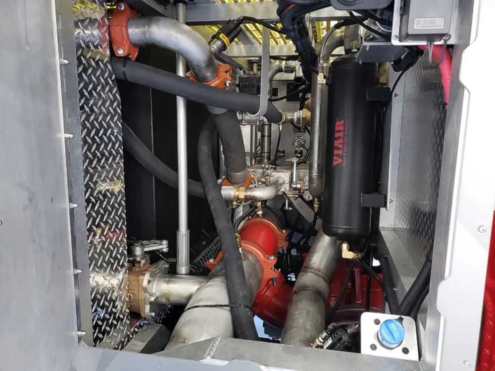 Exterior view of small fire truck showing cab, body compartments, and wheel/tire area.