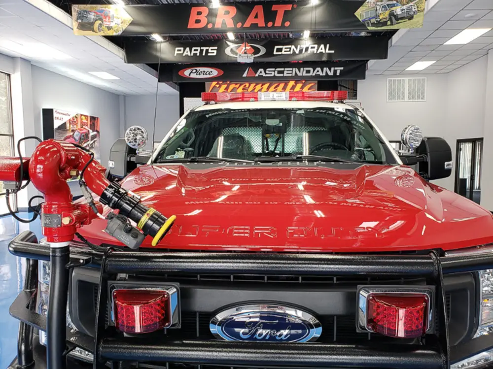 Exterior view of small fire truck showing cab, body compartments, and wheel/tire area.