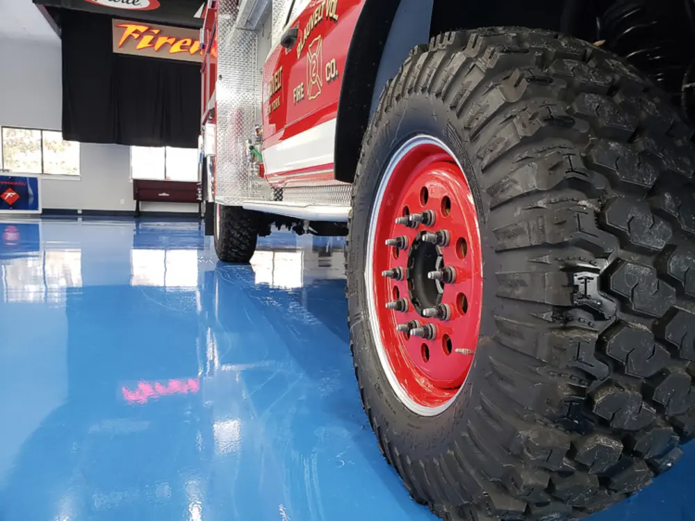 Exterior view of small fire truck showing cab, body compartments, and wheel/tire area.