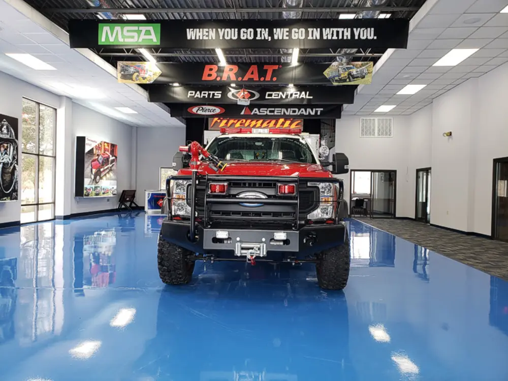 Exterior view of small fire truck showing cab, body compartments, and wheel/tire area.