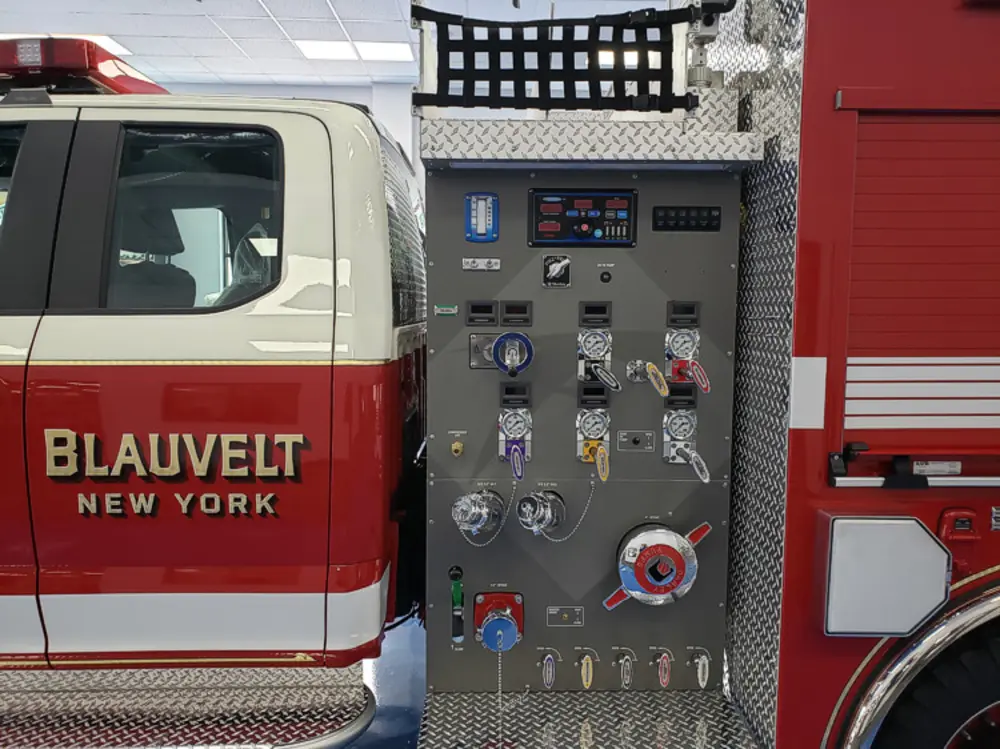 Exterior view of small fire truck showing cab, body compartments, and wheel/tire area.