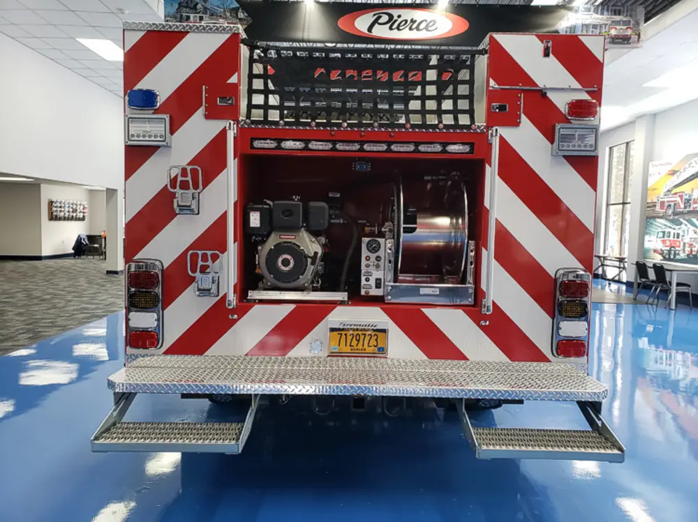 Exterior view of small fire truck showing cab, body compartments, and wheel/tire area.