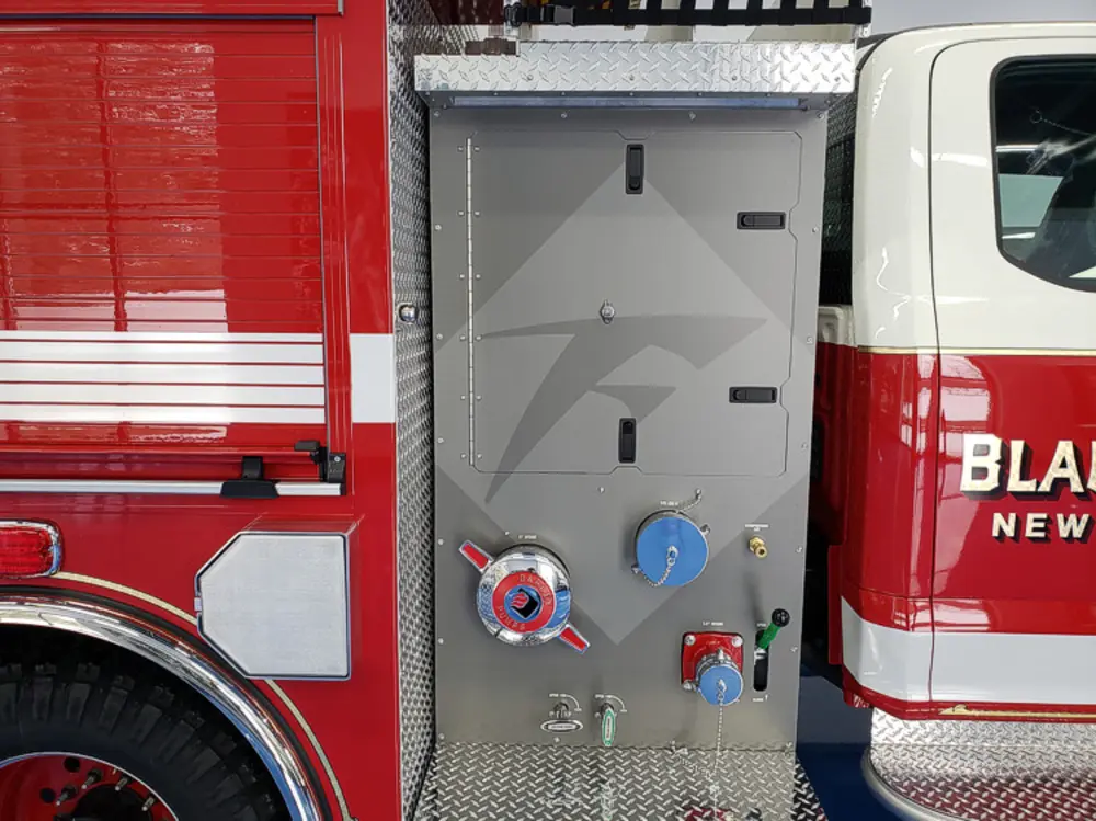 Exterior view of small fire truck showing cab, body compartments, and wheel/tire area.