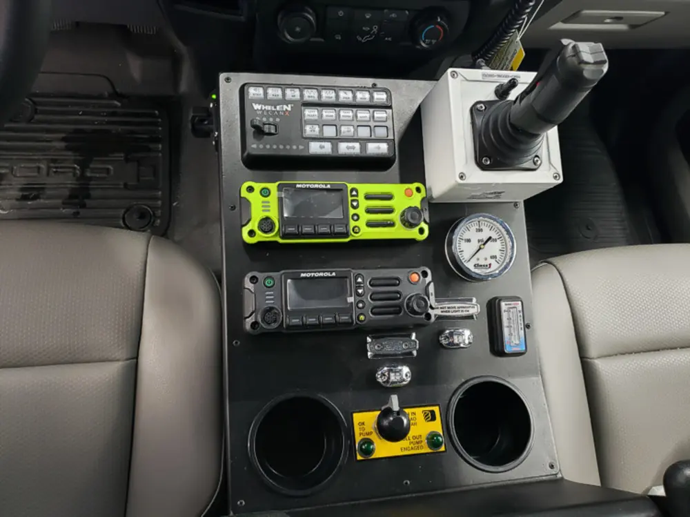 Exterior view of small fire truck showing cab, body compartments, and wheel/tire area.